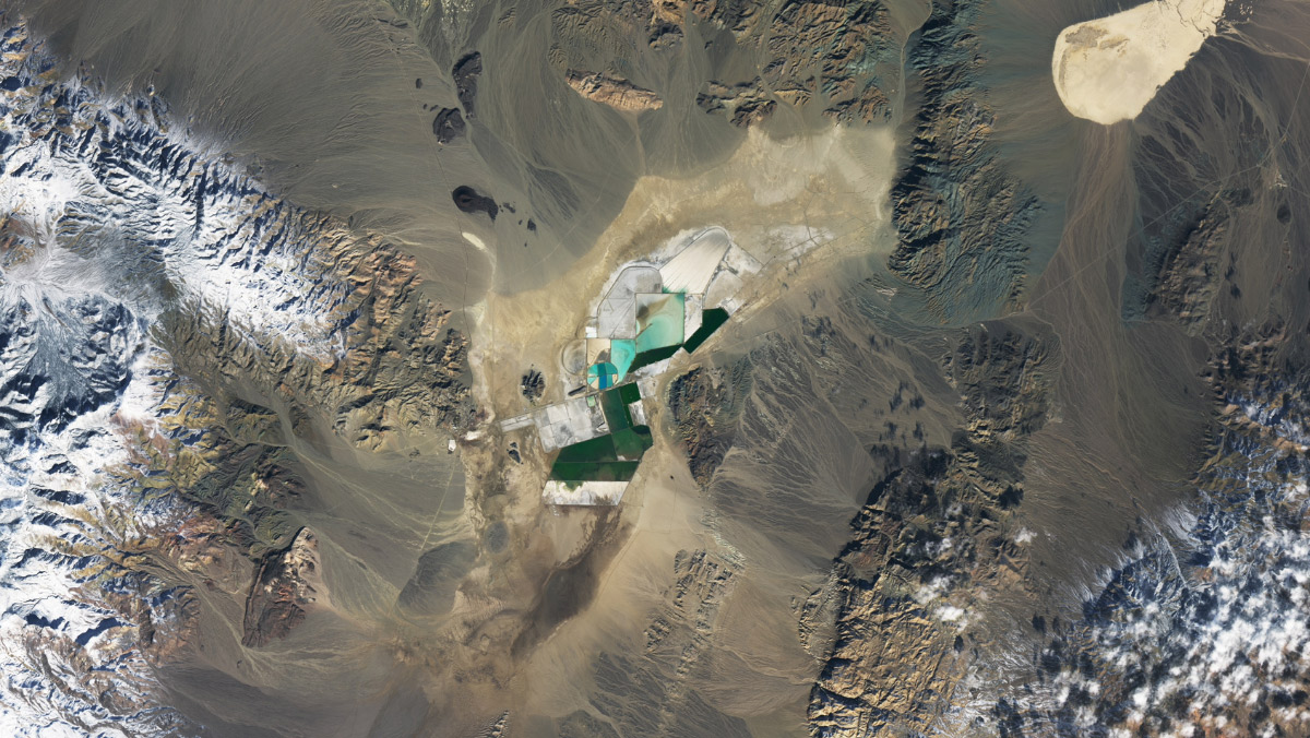 Satellite view of lithium brine ponds surrounded by rugged desert terrain in Argentina.
