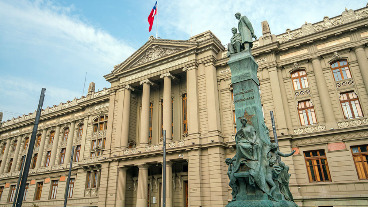 Monument and national flag standing before Chile’s justice palace.