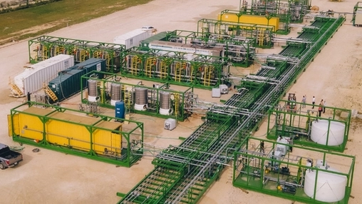 Aerial view of a modular green and yellow lithium extraction facility with tanks and connecting pipes