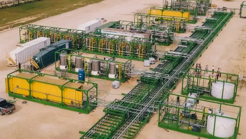 Aerial view of a modular green and yellow lithium extraction facility with tanks and connecting pipes